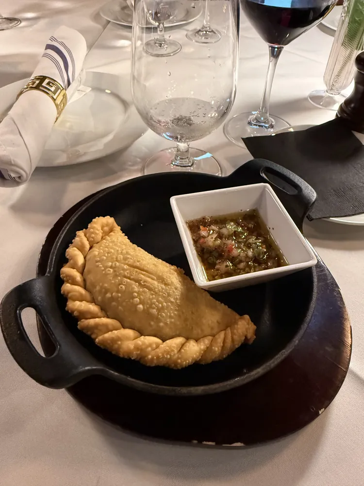 A baked Argentine empanada with chimichurri