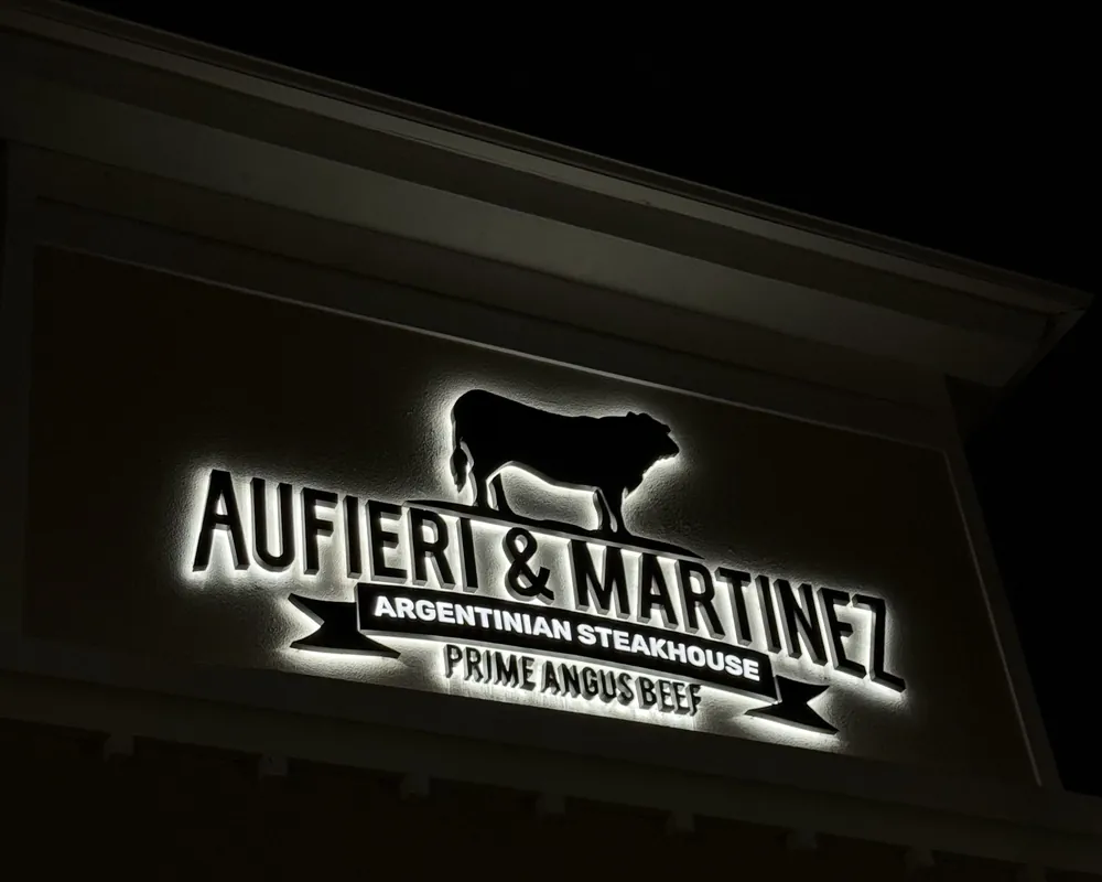 The illuminated Aufieri & Martínez sign at night
